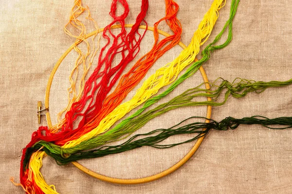 刺繍糸でフープの上に 自然なリネン生地で刺繍フープ 異なる色 天然のリネン生地を背景に刺繍糸の選択 トップビュー — ストック写真