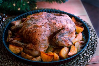 Noel tavuğu patates, otlar ve sehpanın dekorasyonu ile pişirildi. Noel yemeği, şenlikli bir yemek. Masanın yan görüntüsü, yakın plan. Seçici odak
