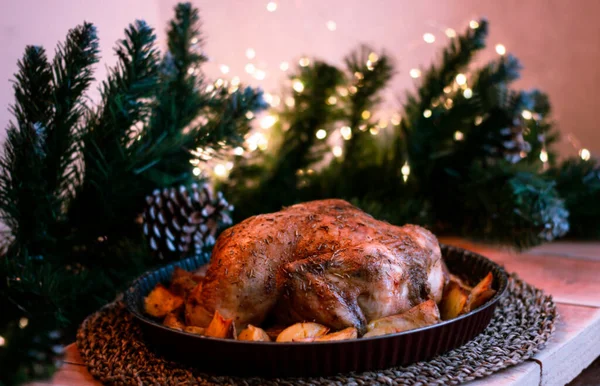 Weihnachtshühnchen gebacken mit Kartoffeln, Kräutern und der Dekoration des gedeckten Tisches. Weihnachtsessen, ein festliches Gericht. Seitenansicht des Tisches. Selektiver Fokus — Stockfoto