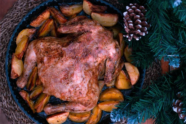Weihnachtshühnchen gebacken mit Kartoffeln, Kräutern und der Dekoration des gedeckten Tisches. Weihnachtsessen, ein festliches Gericht. Blick von oben auf den Tisch, Nahaufnahme — Stockfoto