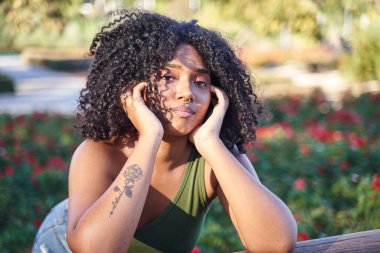 Kıvırcık saçlı, genç bir kadının portresi. Sıkılmış bir bakışla bekliyor..