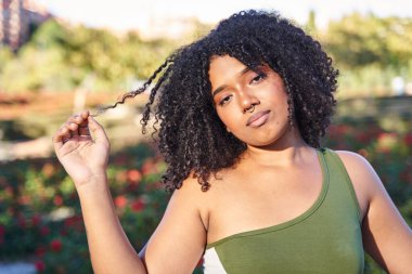 Genç bir kadın kıvırcık saçlarını eliyle tutuyor.