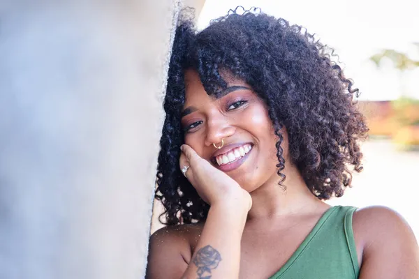 Portrait of beautiful latina woman. Smiling dreamy beautiful latina girl with black curly hair outside in the city.