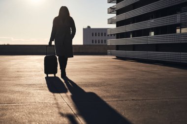 El bagajı olan tanınmayan bir kadın silueti.