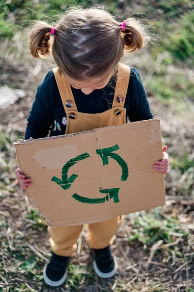 Dziewczyna Dwoma Warkoczami Trzymająca Kartonowy Znak Symbolem Recyklingu — Zdjęcie stockowe