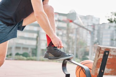 Sahada ayakkabı bağı bağlayan tanınmamış bir basketbolcu.