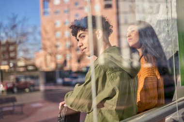 Üniversiteye gitmek için otobüste ya da tramvay durağında bekleyen iki öğrenci. sürdürülebilir ulaşım kavramı.
