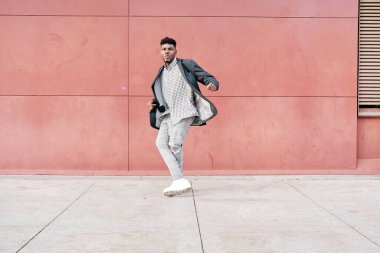 Afro-Amerikalı bir adam dışarıda günlük kıyafetlerle dans ediyor.
