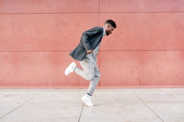 Afro-Amerikalı bir adam dışarıda günlük kıyafetlerle dans ediyor.