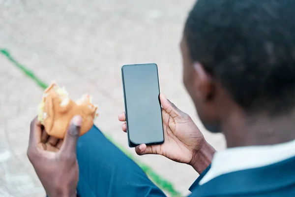 Vista Trasera Hombre Comiendo Una Hamburguesa Con Teléfono Blanco Como — Foto de Stock