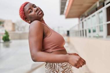 Korkuluklara yaslanan genç bir kadın kameraya bakıyor.