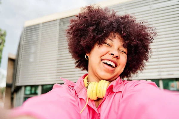 Kıvırcık saçlı genç Afro-Amerikalı kadın selfie çekiyor.