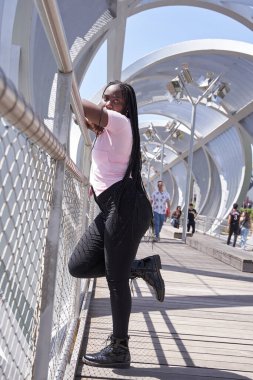 Afro-Amerikan kadın, elinde örgülerle kameraya bakarken poz veriyor.