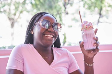 Afro-Amerikalı kadın smoothie içiyor.