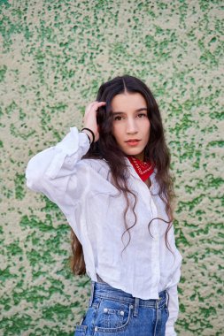 Uzun saçlı genç bir kadının portresi yeşil tonlarda bir duvardaki kameraya bakıyor.