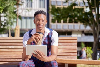 african american young man with tablet computer and take away coffee