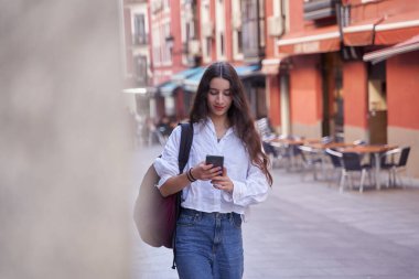 young woman walking using a cellphone in the street