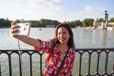 Çekici Latin kız Madrid 'deki emeklilik parkında selfie çekiyor. Genç turist Madrid 'i ziyaret ediyor.