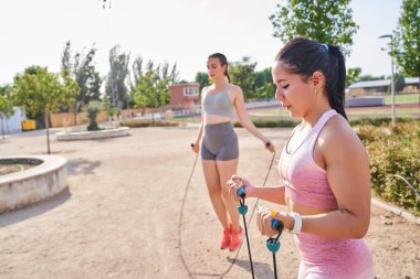 İki kişi egzersiz tahtası yapıyor, iki kadın ve lastik bantlı bir erkek.