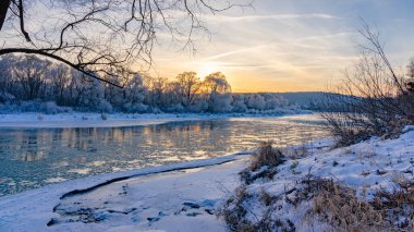 Winter sunset view of the San river and snow-covered trees