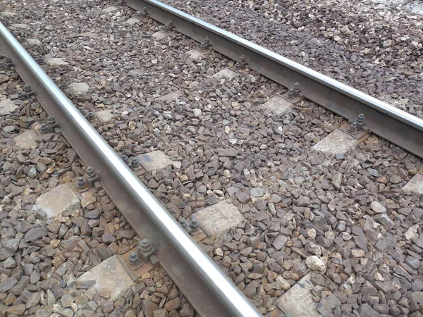金属製のレールとコンクリート製のベッドはほとんど鉄道の砂利で覆われています — ストック写真