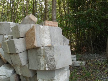 İnşaat alanının yakınındaki ormanda, düşük kalite ve hasarlı beton bloklar, sahte bir kaplama ve köpük yalıtımı ile.