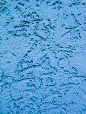 Dekoratif alçıyla kaplı bir duvara soyut bir çizim. Sakin nötr mavi renk şemasında tek renkli arkaplan.