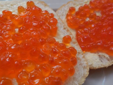 Lezzetli, lezzetli kırmızı havyar beyaz ekmek üzerine tereyağlı, beyaz tabakta.