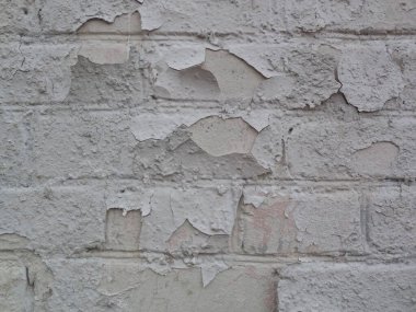Büyük beyaz alçı parçaları eski tuğla duvardan soyuluyor..