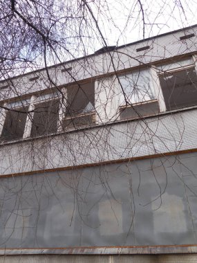 Terk edilmiş bir anaokulunun bölgesi. Binada kırık pencereler var, pencereler demir çarşaflarla kaplı..