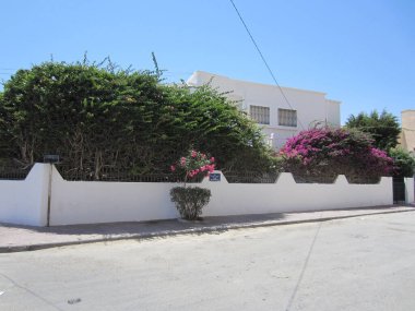 Susa, Tunus, Temmuz 2013. Beyaz çitin arkasında özel mülk. İki katlı bina çiçek açan begonviller ve zakkumlarla çevrili..