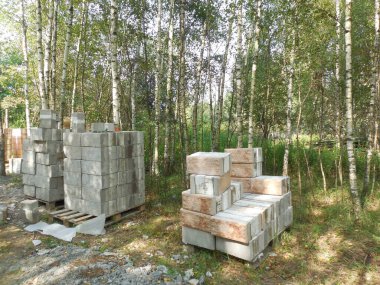Beton bloklar, taklit taş ve köpük yalıtımına (yalıtım) bakıyor. İnşaat alanının yakınındaki inşaat malzemeleri bir kır evi inşaatı için hazırlanıyor..