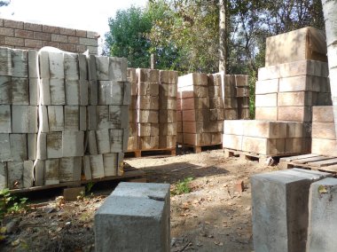 Beton bloklar, taklit taş ve köpük yalıtımına (yalıtım) bakıyor. İnşaat alanının yakınındaki inşaat malzemeleri bir kır evi inşaatı için hazırlanıyor..