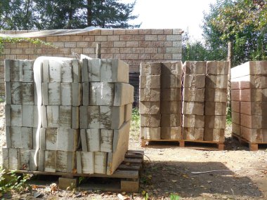 Beton bloklar, taklit taş ve köpük yalıtımına (yalıtım) bakıyor. İnşaat alanının yakınındaki inşaat malzemeleri bir kır evi inşaatı için hazırlanıyor..