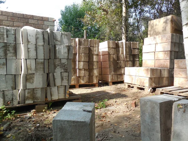 Beton bloklar, taklit taş ve köpük yalıtımına (yalıtım) bakıyor. İnşaat alanının yakınındaki inşaat malzemeleri bir kır evi inşaatı için hazırlanıyor..