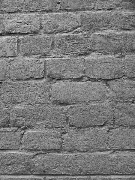 Старая кирпичная неровная штукатурная стена с трещинами. Черно-белое монохромное фото.