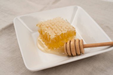 Arkaplanda bal peteği olan bir tabak kaşık, yakın görüş, bal peteği üzerine organik bal.