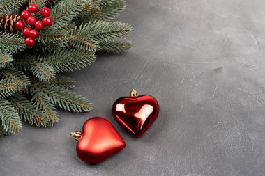 Gri arka planda iki kalp şeklindeki baloncuklu yeşil Noel çelengi. Kopyalama alanı olan üst görünüm