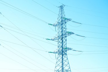 Mavi gökyüzüne karşı yüksek voltajlı elektrik direkleri