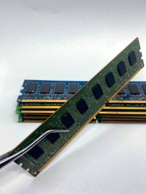 Bellek belleği kıskaç yakın görüntüsünde arkaplanda beyaz üzerine izole edilmiş bir yığın RAM ile