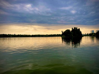 Landscape view of a lake with trees and sky reflections on it at sunset