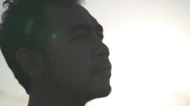 Portrait Asian Indonesian Male Hopeful Thoughtful and Confident Face Illuminated by The Sun in Dramatic Slow Motion