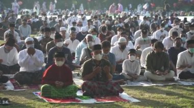 Bali, Indonesia - May 2 2022: Muslims Gather Celebrate Eid al-Fitr Salah Praying in a Park in Denpasar