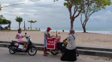 Bali, Endonezya - CIRCA 2022: Endonezyalı Kadınlar Sahilde Motosiklet Sokak Yemeği Satıyor
