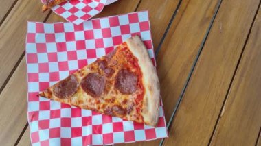 New York Style Pizza Classic American Pepperoni Parmesan Cheese and Red Chili Flakes on Red and White Paper on Wooden Table