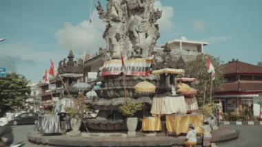 Gray stone Patung Catur Muka monument on roundabout shows Lord Brahma looking in four Directions in Semarapura Klungkung Bali, Indonesia