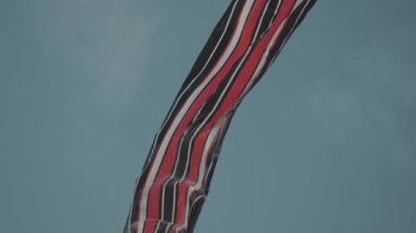 Balinese Traditional Kites JANGGAN (Red White Black Long Tail Bird Dragon) on Bali Kite Festival Summer Blue Sky Slow Motion