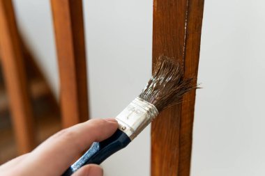 Tahta korkulukları boyarken fırça tutan bir el.