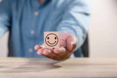 Adam odun küpü bloğu veriyor, elinde gülümseme simgesi, müşteri hizmetleri en iyi iş derecelendirme deneyimi. Memnuniyet araştırma konsepti