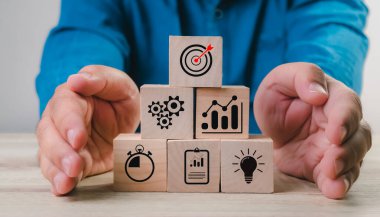 Business goal achievement concept of business strategy and action plan. businessman hand wooden cube block stacking with icon